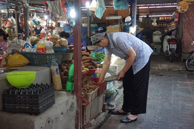 Gemüse Marktstand Vietnamesische Frau gebückt über Angebot am Gemüse Marktsstand
