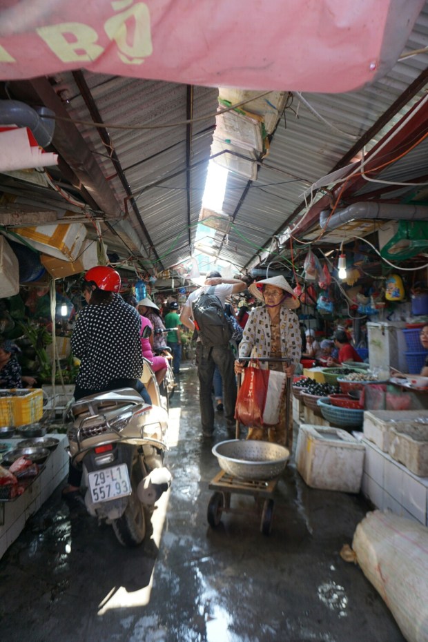 Hanoi Markt Gasse im Markthalle mit Marktstände, Kunden auf Roller, Verkäuferinnen und Waren